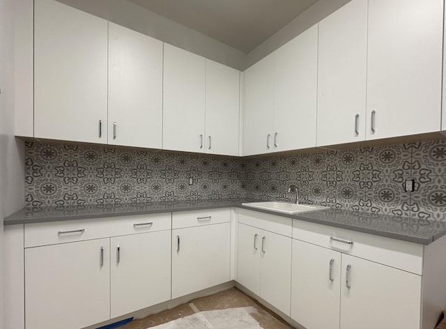 kitchen featuring backsplash, white cabinetry, and a sink