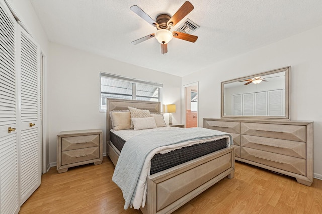 bedroom featuring a textured ceiling, ceiling fan, light hardwood / wood-style flooring, and a closet