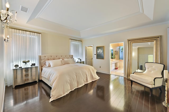 bedroom with ensuite bath, a raised ceiling, dark hardwood / wood-style floors, a notable chandelier, and crown molding