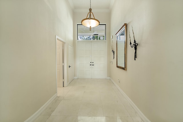 hallway featuring light tile patterned floors, a towering ceiling, and crown molding