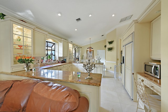 kitchen featuring kitchen peninsula, crown molding, cream cabinets, pendant lighting, and lofted ceiling