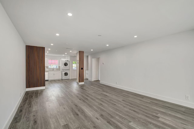 unfurnished living room with wood-type flooring and stacked washer / dryer