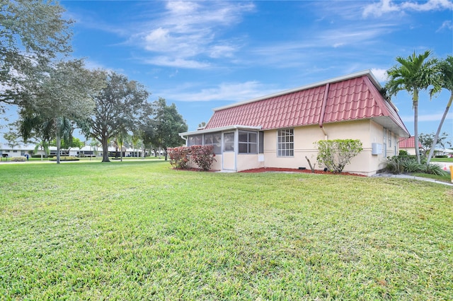 view of side of home featuring a lawn and a sunroom