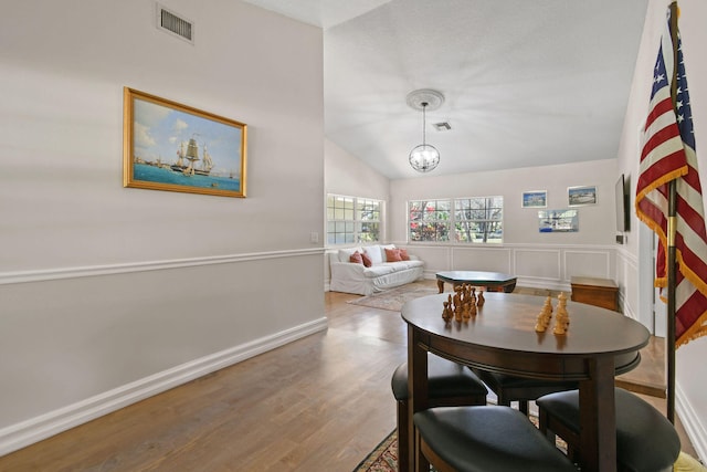 dining room with wood-type flooring, vaulted ceiling, and a notable chandelier