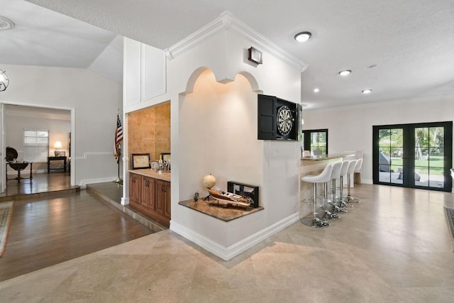 hall featuring french doors, ornamental molding, a textured ceiling, vaulted ceiling, and hardwood / wood-style flooring