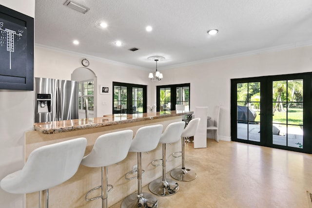 kitchen with light stone countertops, french doors, hanging light fixtures, and stainless steel fridge with ice dispenser