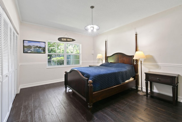 bedroom with a closet, dark wood-type flooring, and ornamental molding