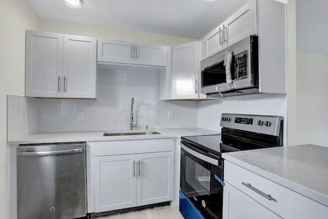 kitchen with tasteful backsplash, sink, white cabinets, and appliances with stainless steel finishes