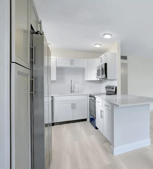 kitchen with white cabinets, appliances with stainless steel finishes, and light hardwood / wood-style floors