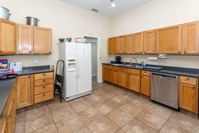 kitchen with white fridge with ice dispenser, light tile patterned floors, stainless steel dishwasher, and sink