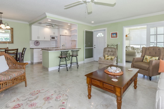 tiled living room with ceiling fan with notable chandelier, a textured ceiling, and ornamental molding