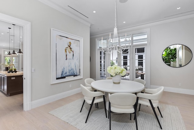 dining room featuring light hardwood / wood-style floors, crown molding, and an inviting chandelier