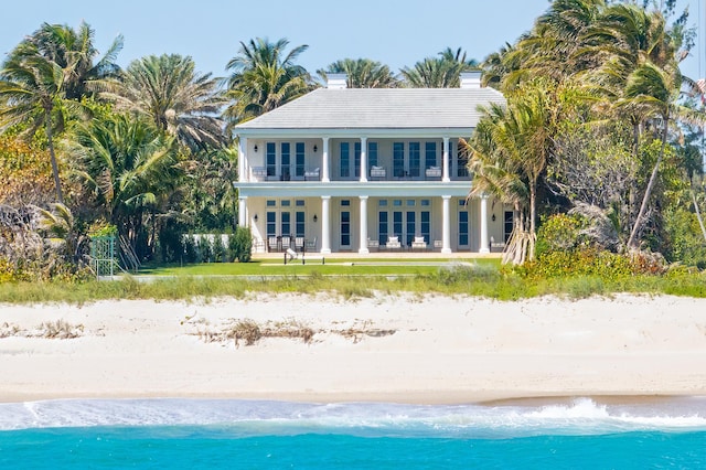 rear view of property featuring french doors, a water view, and a beach view