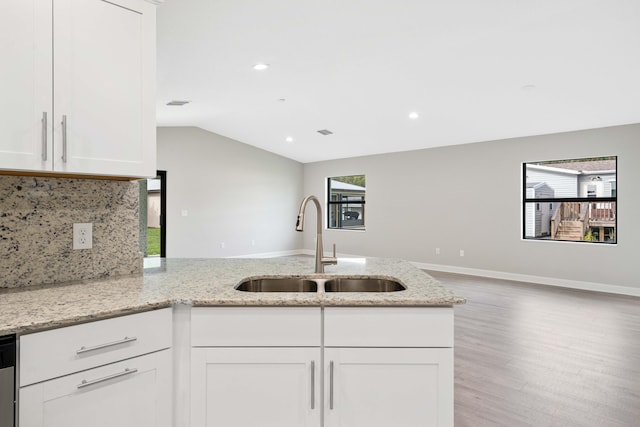 kitchen with light wood-type flooring, sink, white cabinetry, and light stone counters