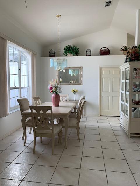 tiled dining space featuring vaulted ceiling