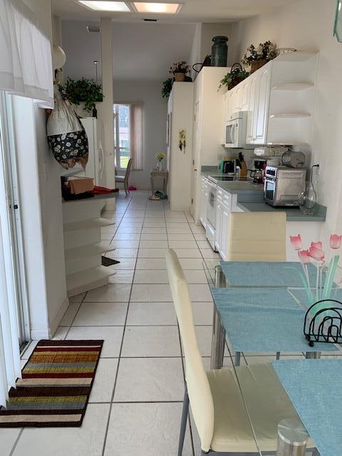 kitchen featuring white appliances, white cabinets, and light tile patterned flooring