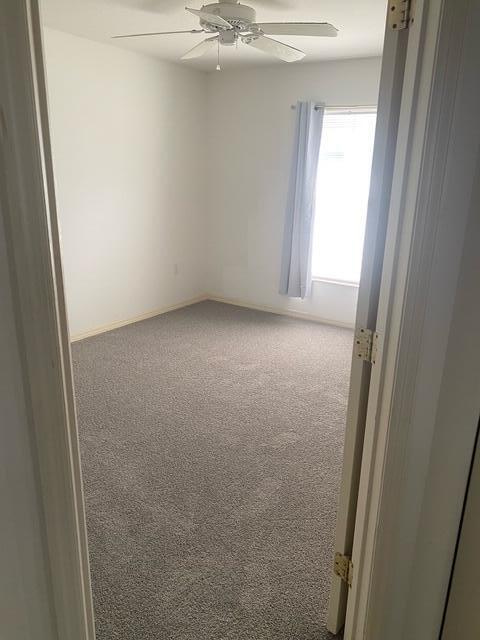 empty room with ceiling fan and carpet