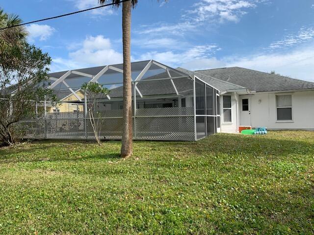 rear view of house with a yard and glass enclosure