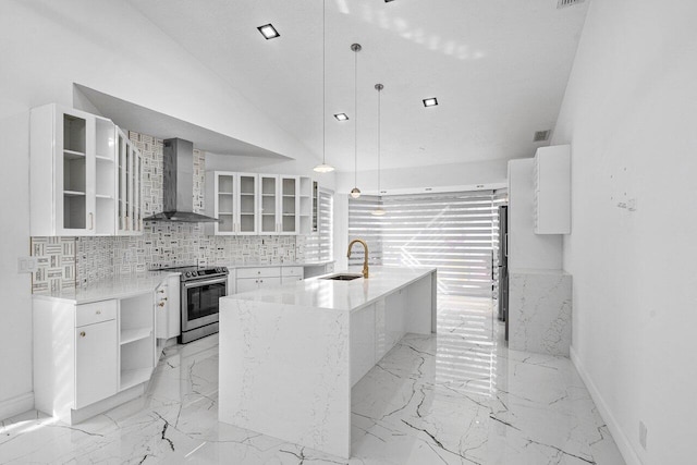 kitchen with hanging light fixtures, wall chimney range hood, stainless steel electric range, a kitchen island with sink, and white cabinets