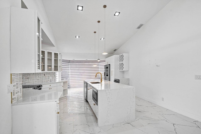 kitchen featuring light stone countertops, sink, a center island with sink, white cabinetry, and hanging light fixtures