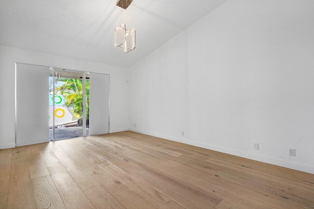 unfurnished room with vaulted ceiling, an inviting chandelier, and light hardwood / wood-style flooring