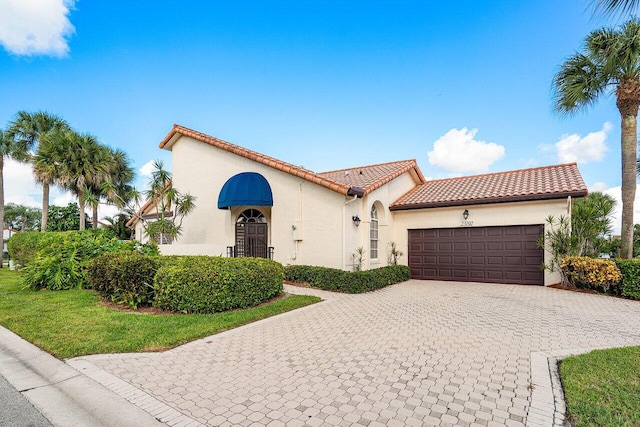 mediterranean / spanish home featuring a front yard and a garage