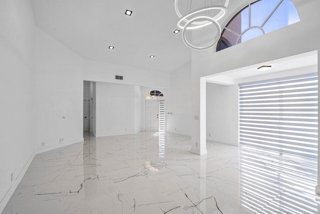 unfurnished living room with high vaulted ceiling and a chandelier