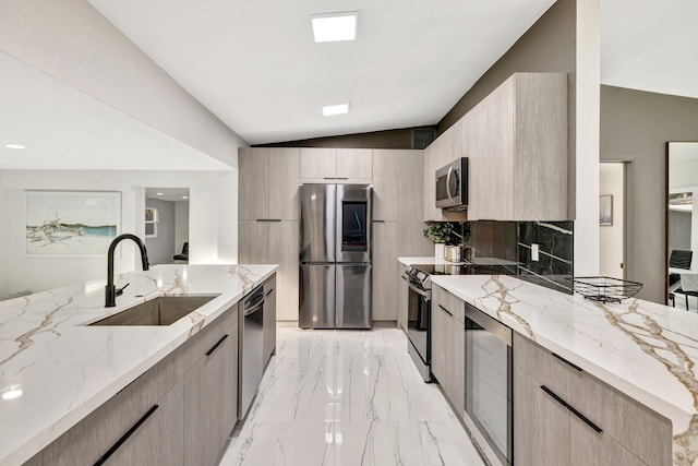 kitchen featuring light stone countertops, sink, stainless steel appliances, lofted ceiling, and light brown cabinetry