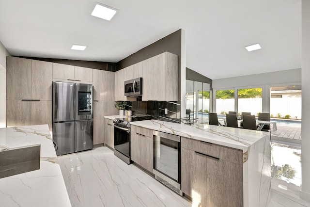 kitchen with kitchen peninsula, light stone counters, stainless steel appliances, and vaulted ceiling