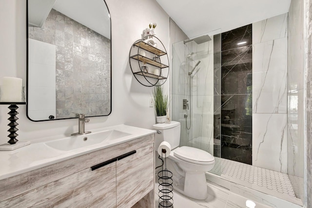 bathroom featuring a tile shower, vanity, and toilet