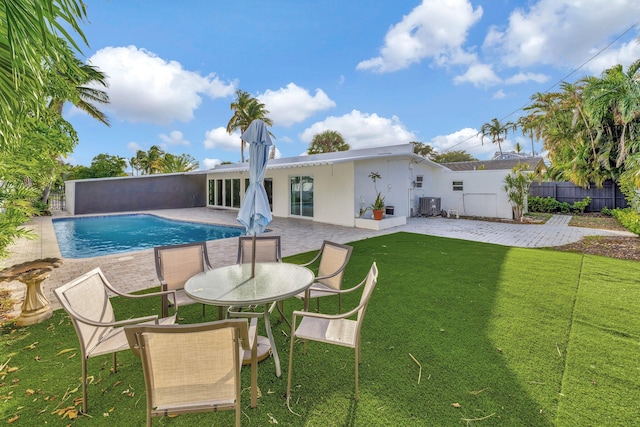 rear view of house with a fenced in pool, a patio area, a yard, and central air condition unit