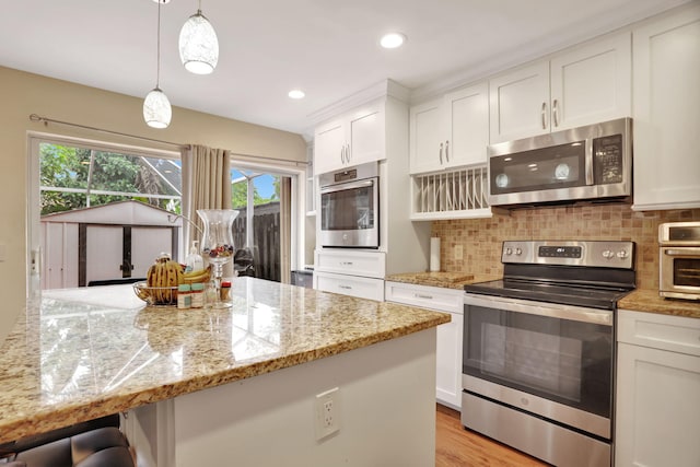 kitchen featuring white cabinetry, hanging light fixtures, and stainless steel appliances