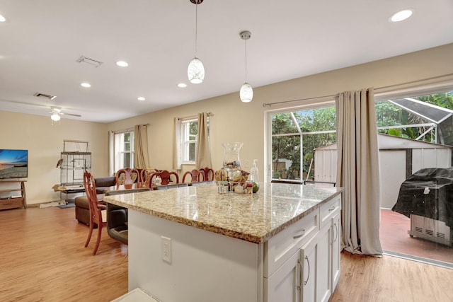 kitchen featuring plenty of natural light, white cabinets, light hardwood / wood-style floors, and decorative light fixtures