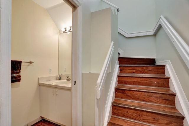 stairs with sink, vaulted ceiling, and hardwood / wood-style flooring