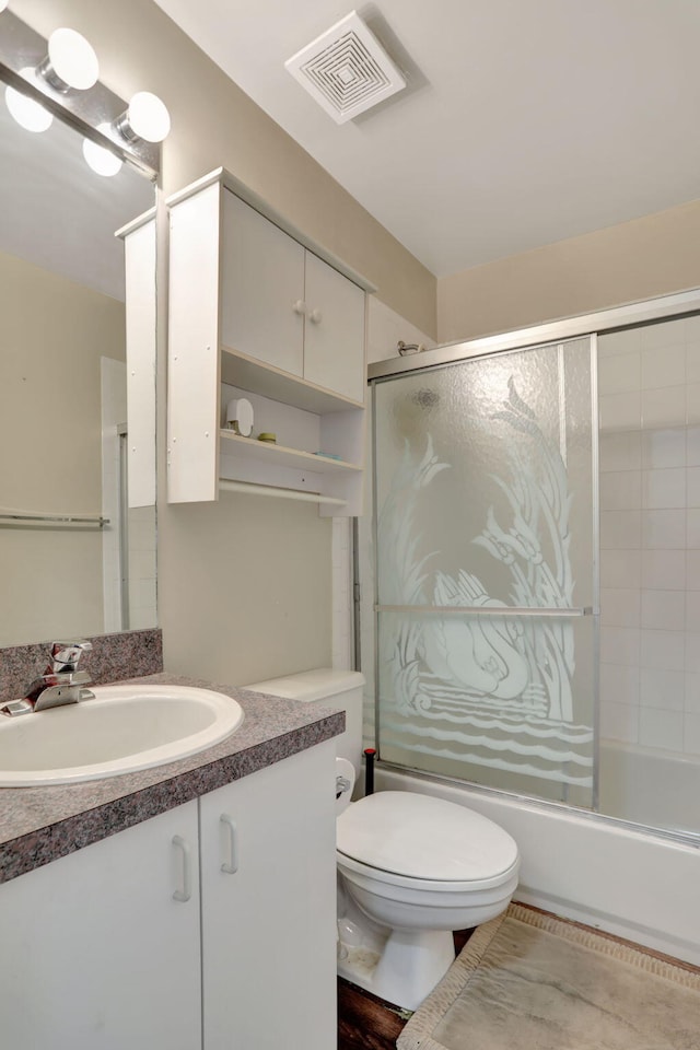 full bathroom featuring combined bath / shower with glass door, vanity, and toilet