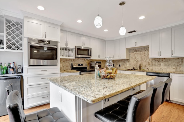 kitchen featuring white cabinets, decorative light fixtures, light wood-type flooring, and stainless steel appliances