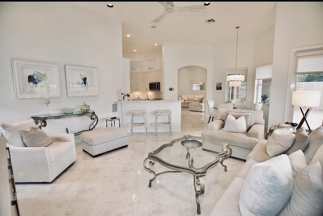 living room with ceiling fan and a high ceiling