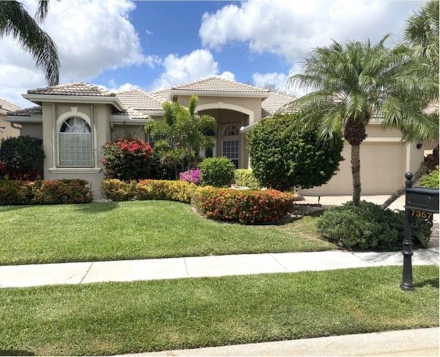 mediterranean / spanish house featuring a garage and a front yard