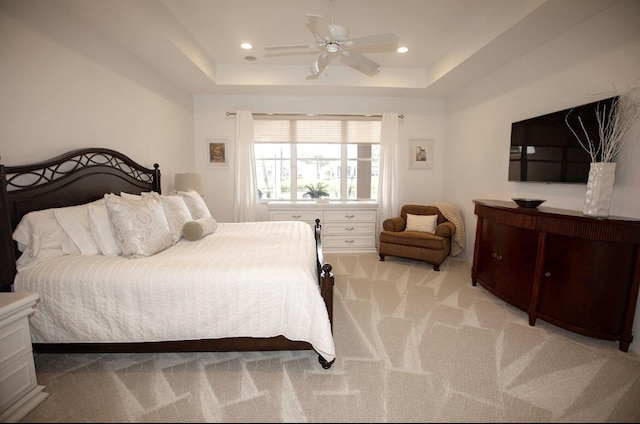 carpeted bedroom featuring a raised ceiling and ceiling fan