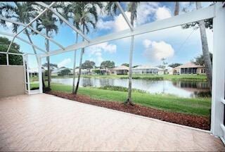 view of patio with a lanai and a water view