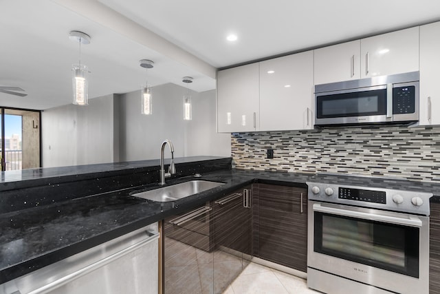 kitchen featuring white cabinets, hanging light fixtures, sink, dark stone countertops, and appliances with stainless steel finishes