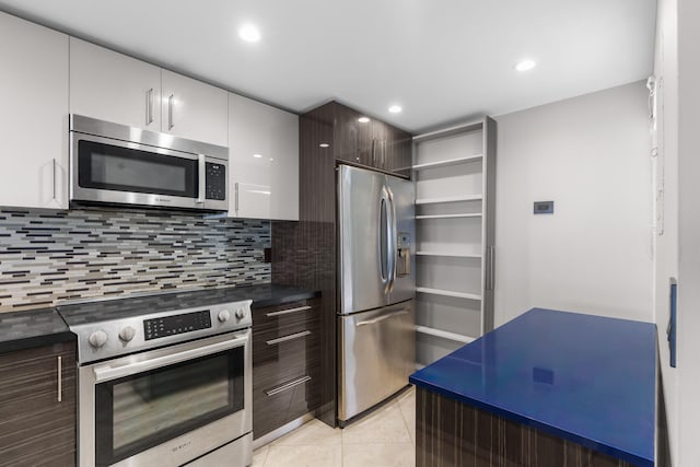 kitchen with dark brown cabinetry, light tile patterned flooring, decorative backsplash, white cabinets, and appliances with stainless steel finishes