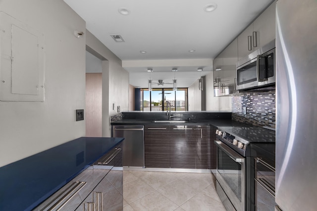 kitchen with backsplash, electric panel, sink, light tile patterned floors, and appliances with stainless steel finishes