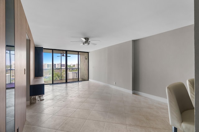 spare room with ceiling fan, expansive windows, and light tile patterned flooring