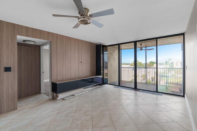 interior space with light tile patterned floors, expansive windows, ceiling fan, and wooden walls