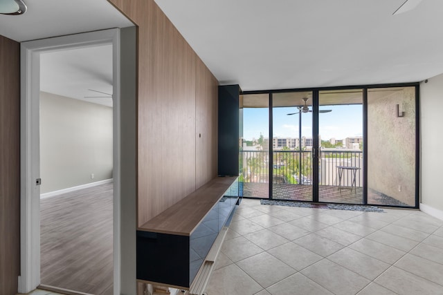 empty room featuring ceiling fan, light hardwood / wood-style floors, and a wall of windows