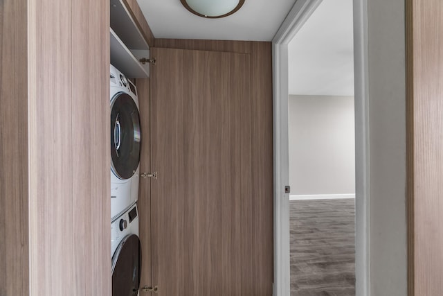 washroom featuring stacked washer and dryer and dark wood-type flooring