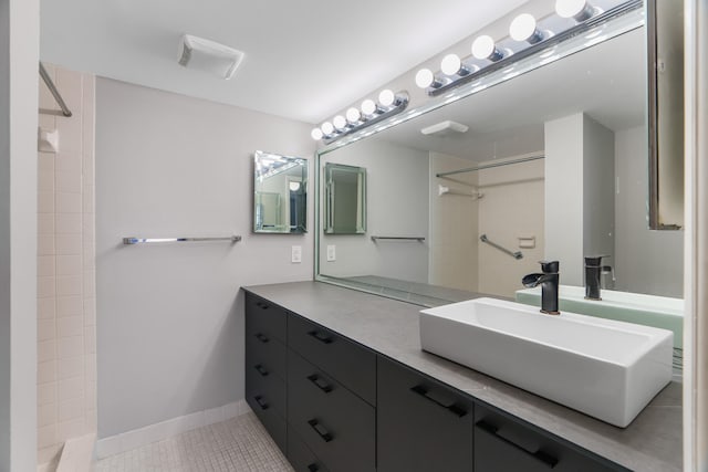 bathroom featuring tile patterned flooring, vanity, and a tile shower