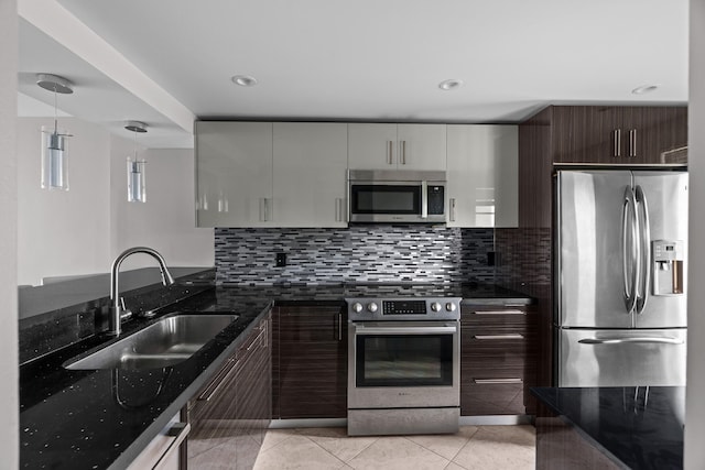 kitchen featuring dark stone counters, dark brown cabinetry, stainless steel appliances, sink, and decorative light fixtures