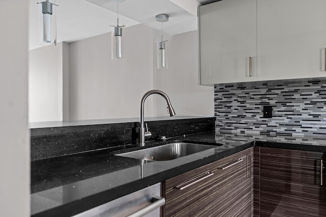 kitchen with dark stone counters, sink, decorative light fixtures, white cabinetry, and dark brown cabinetry